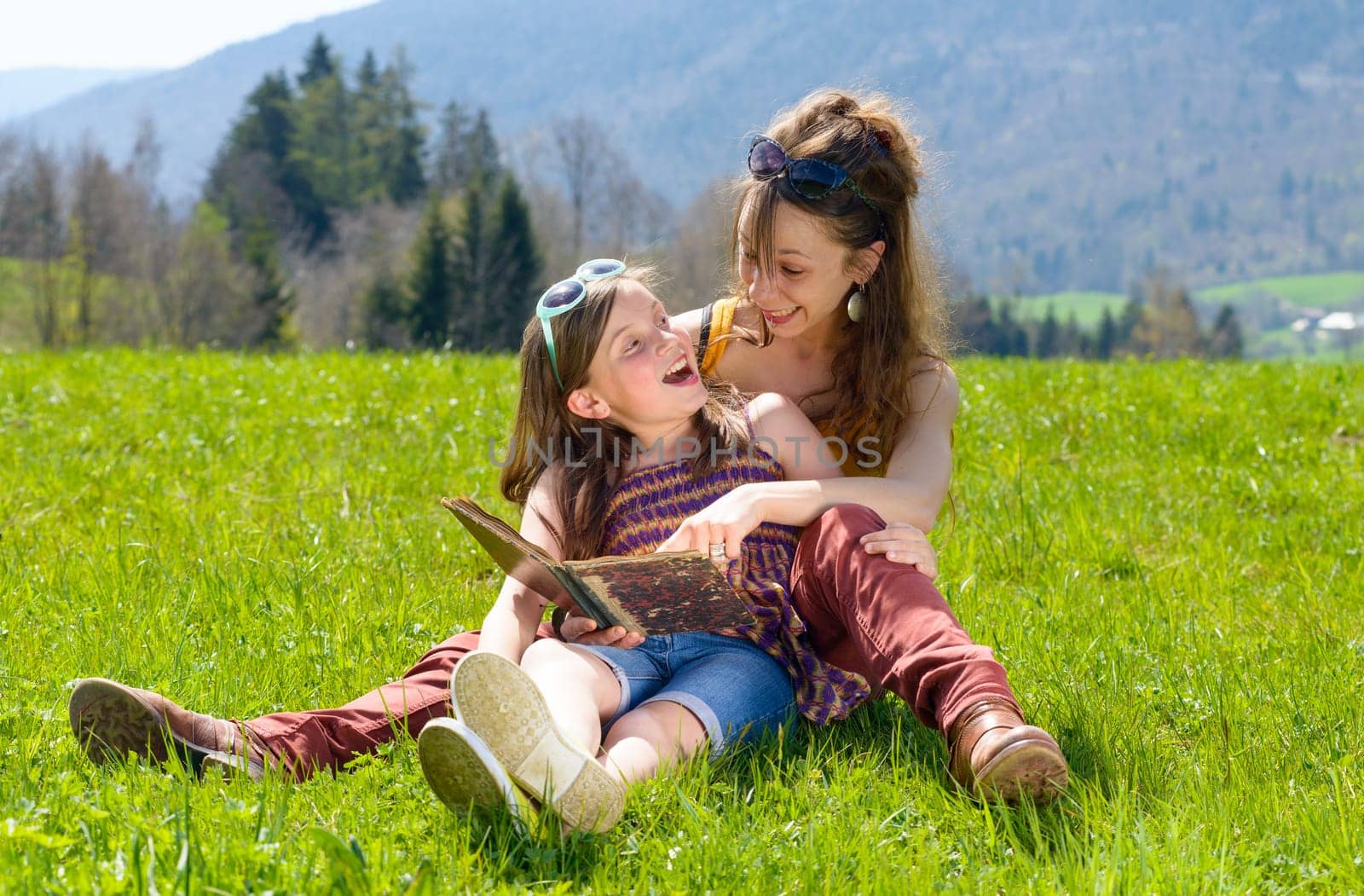 Mom and daughter reading a book in nature