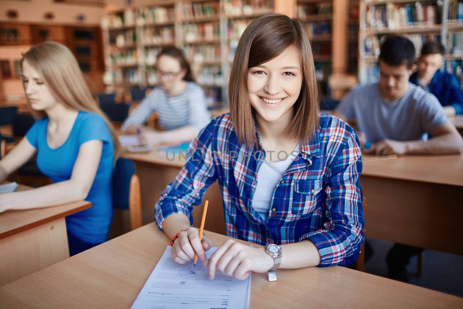 Successful teenager sitting by desk in college