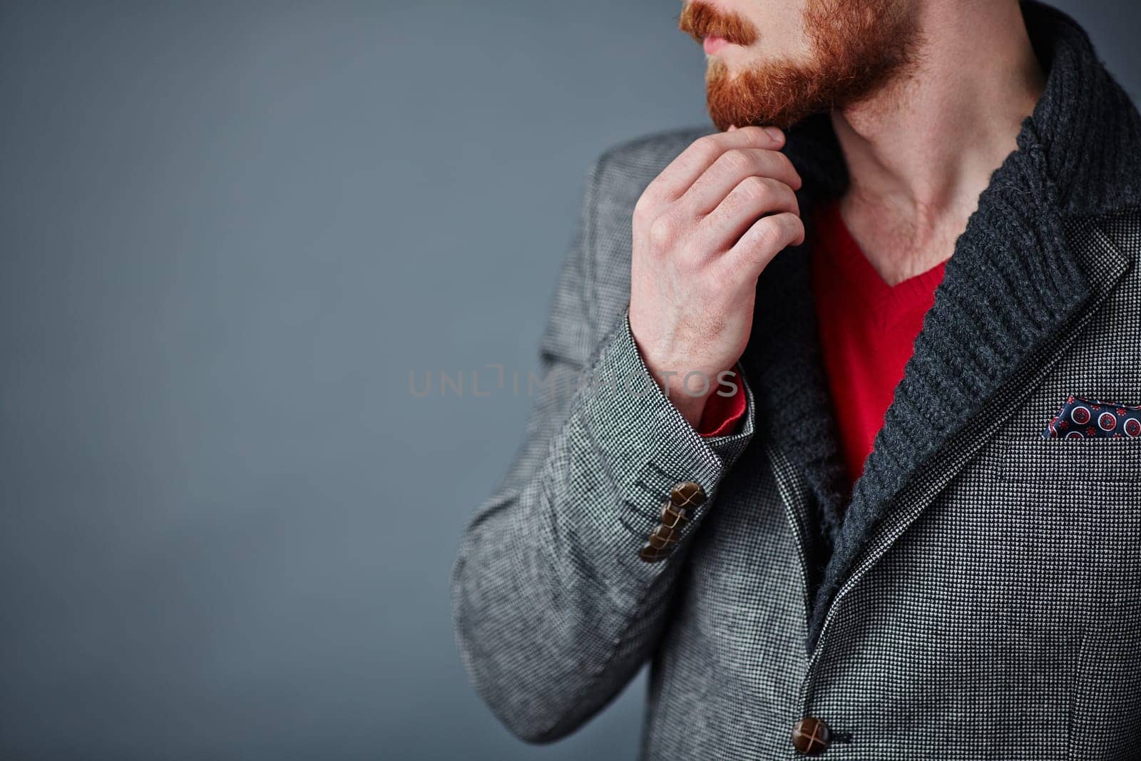 Pensive young man in smart casualwear touching his beard