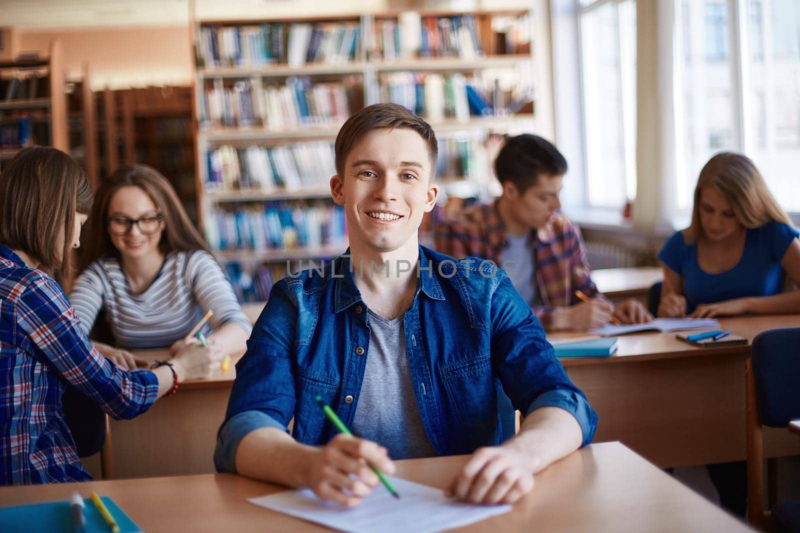 Teenage guy in casualwear looking at camera by desk