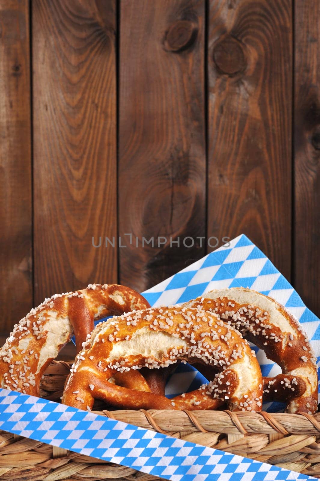 Three original Bavarian lye pretzels with salt in front of a wooden wall