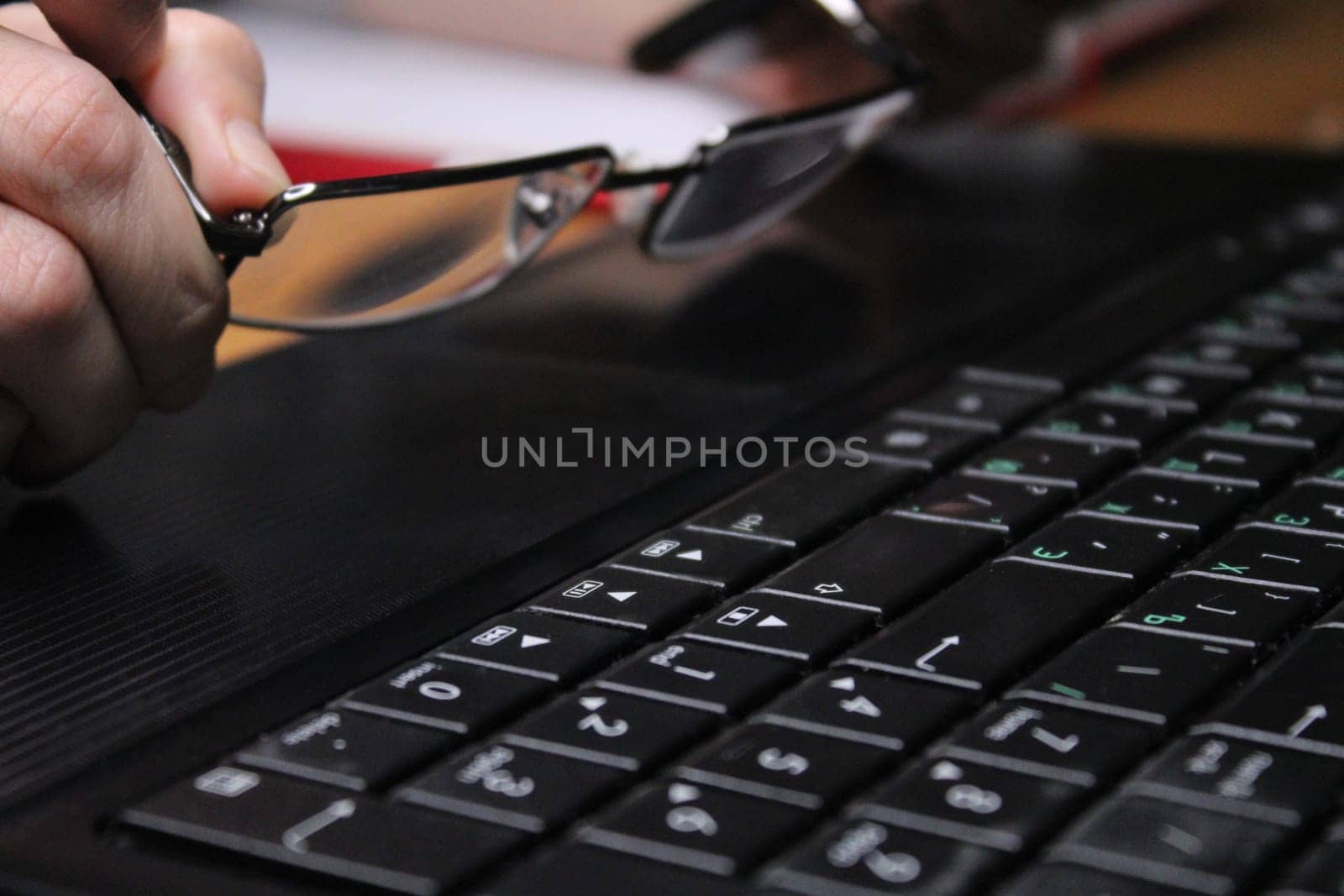A girl sitting at a laptop holds glasses in her hands. Business concept. Work from home..