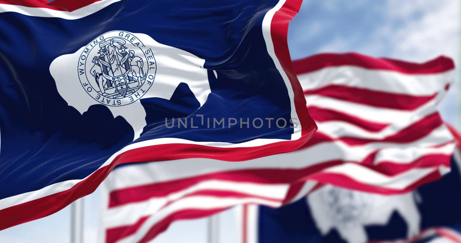 The Wyoming state flag waving along with the national flag of the United States of America. Wyoming is a state in the Mountain West subregion of the Western United States