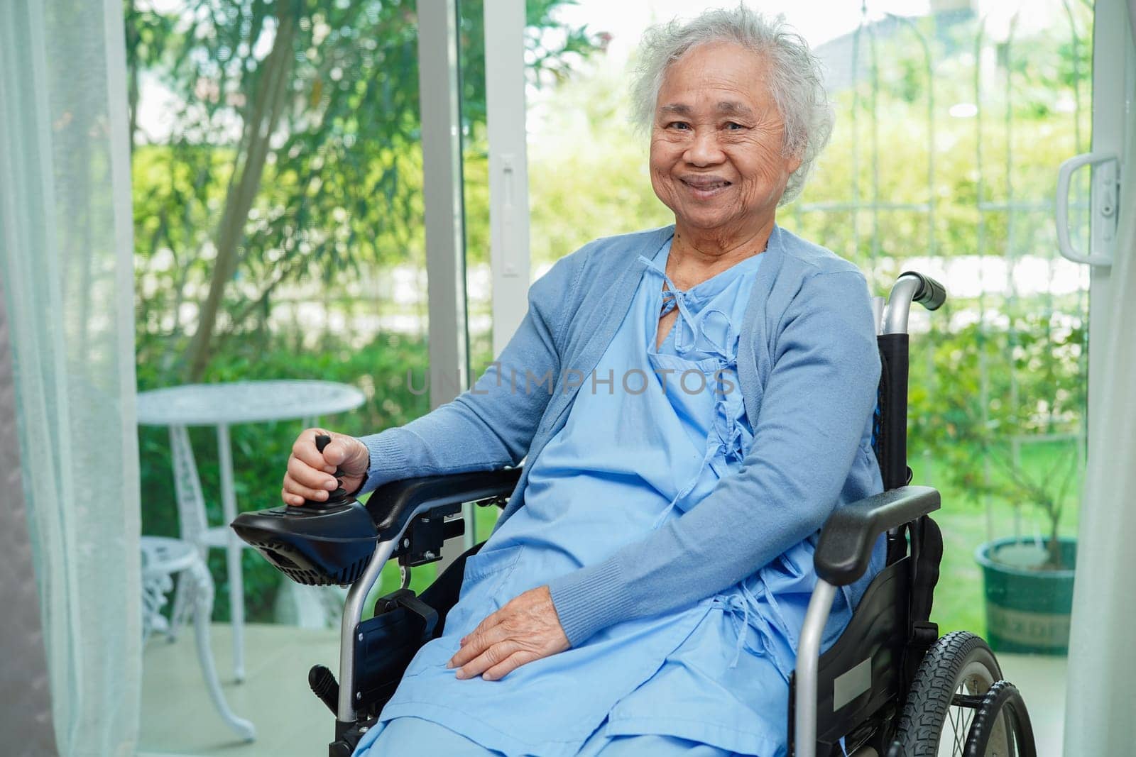 Asian elderly woman disability patient sitting on electric wheelchair in park, medical concept.