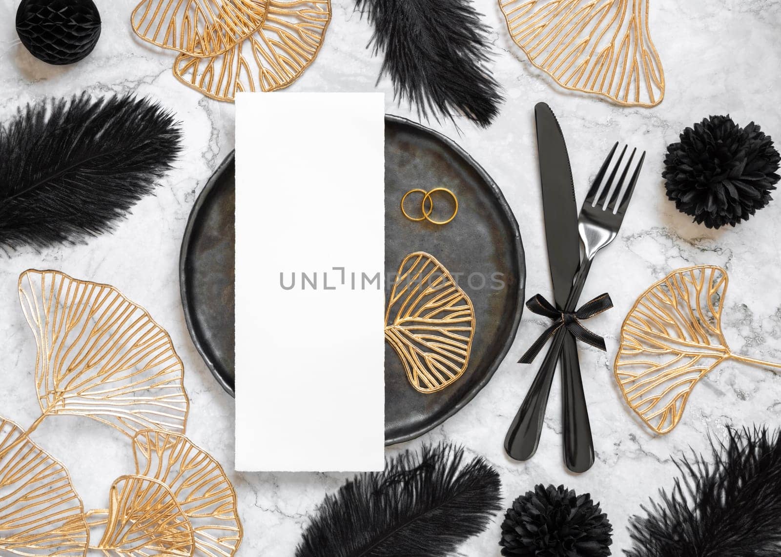 Black and golden wedding table setting with a blank card and rings top view, mockup. Elegant flat lay with vertical menu or Invitation paper card, wedding or holiday stationery template