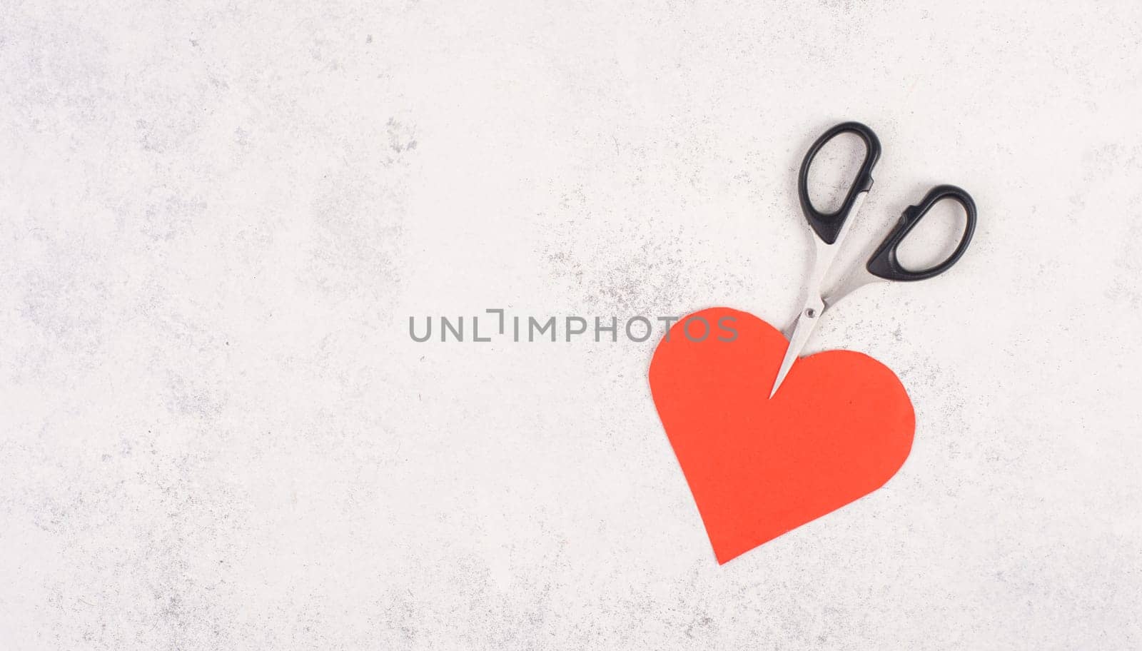 Red heart cut by the scissors, symbol for broken relationship, love and emotion concept, divorce and breakup problems