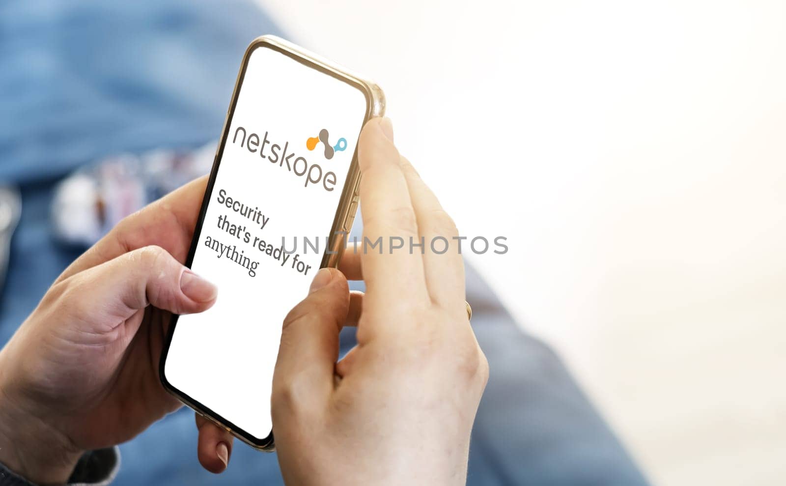 San Francisco, CA, US, May 2022: Female hands holding a phone with Netskope company web page on screen in her living room. Netskope is a security software company