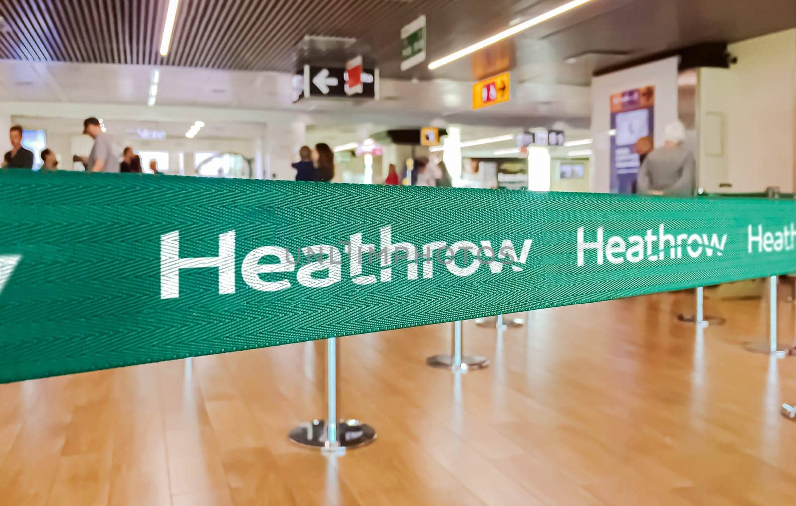 London, UK, May 2022: Green belt barrier with white London Heathrow International Airport logo. American Airlines is a major US-based airline. Travel and airport security