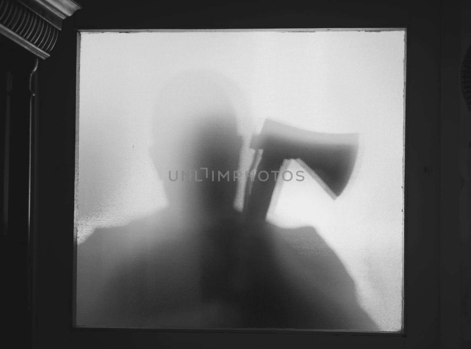 Horror, halloween background - Shadowy figure behind glass of a man holding an axe
