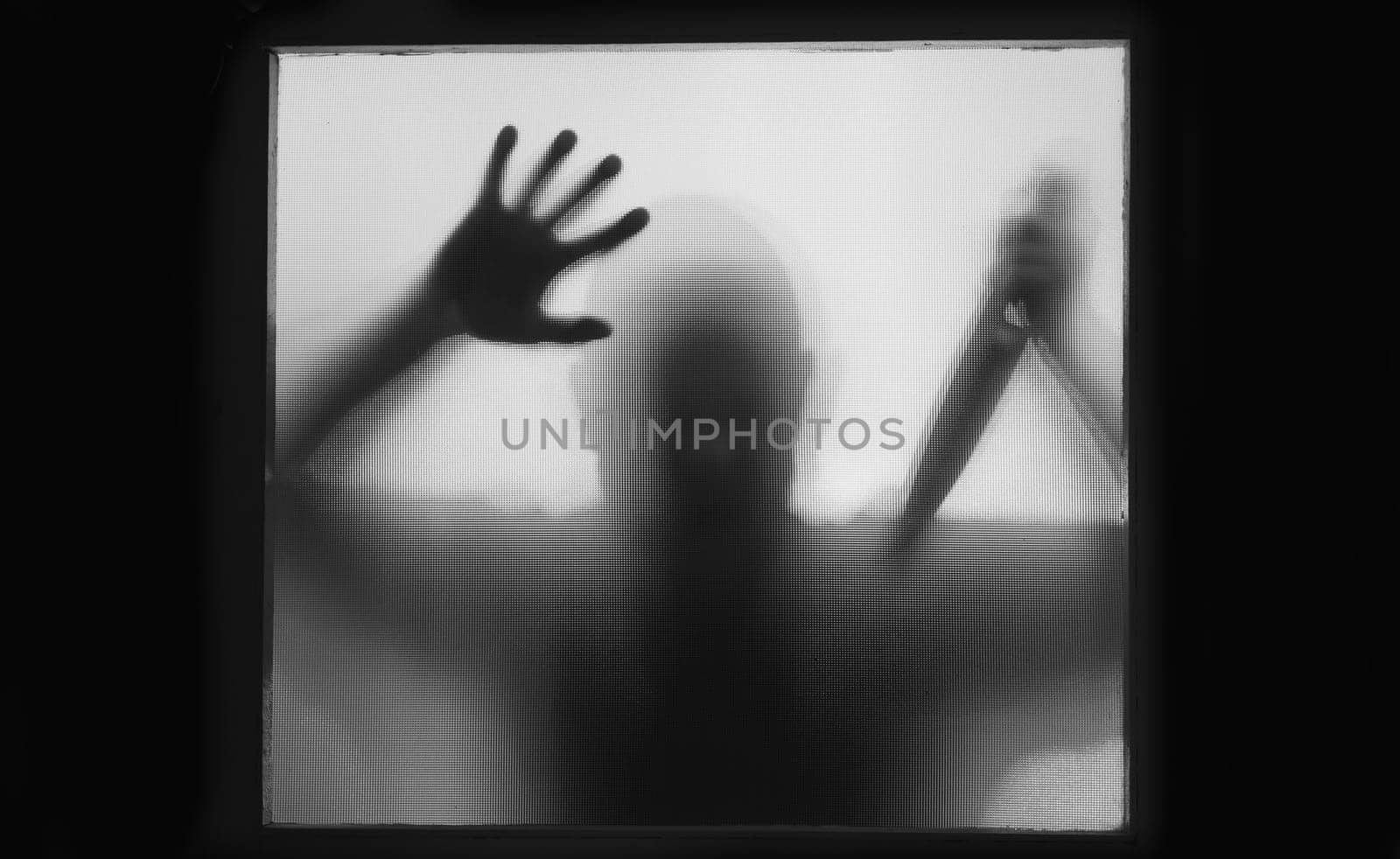 Horror, halloween background - Shadowy figure behind glass of a man holding a knife