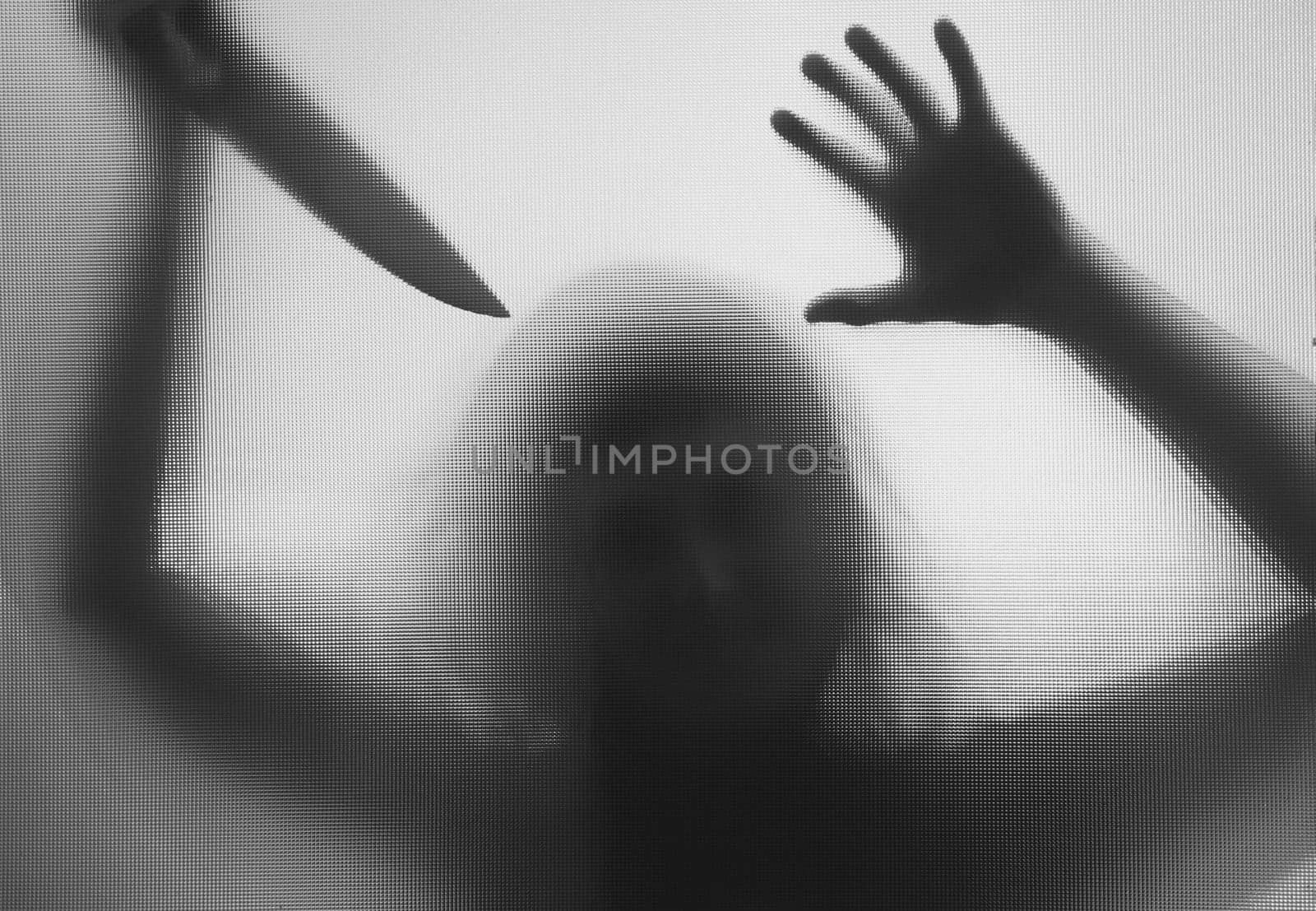 Horror, halloween background - Shadowy figure behind glass holding a knife