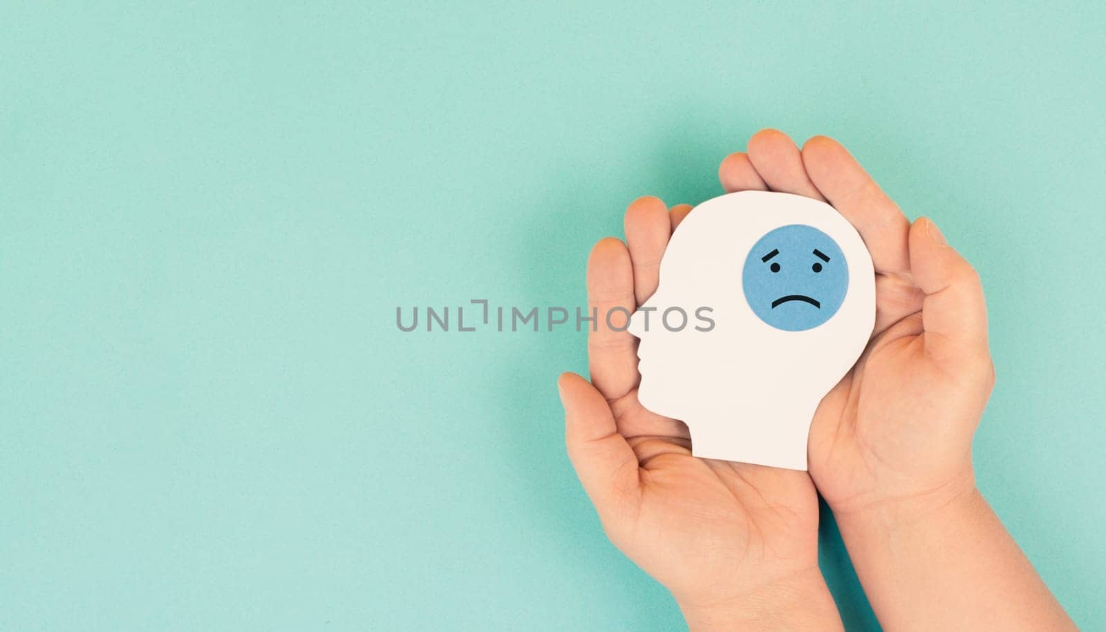 Holding a head with a sad face in the hands, mental health concept, negative mindset, depression, support and evaluation symbol
