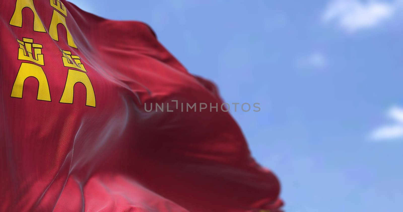 The Region of Murcia flag waving in the wind on a clear day. Region of Murcia is an autonomous community of Spain located in the southeast part of the Iberian Peninsula