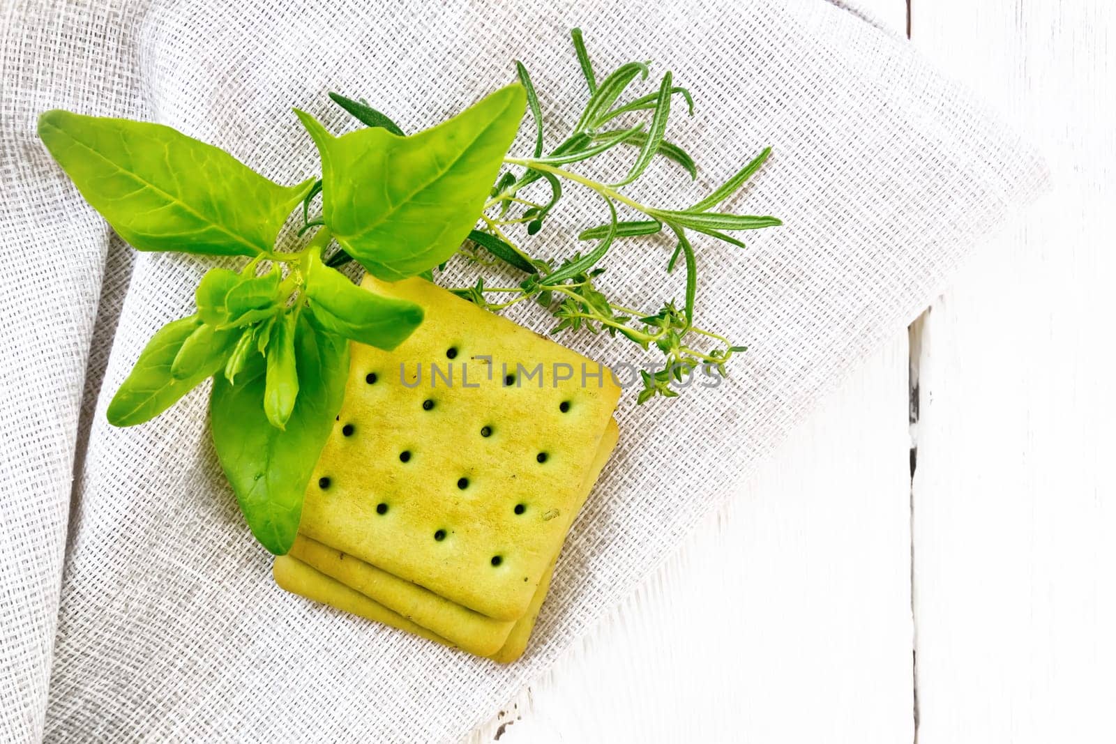 Dry cookies with spinach, rosemary and thyme on a napkin on background of wooden board from above