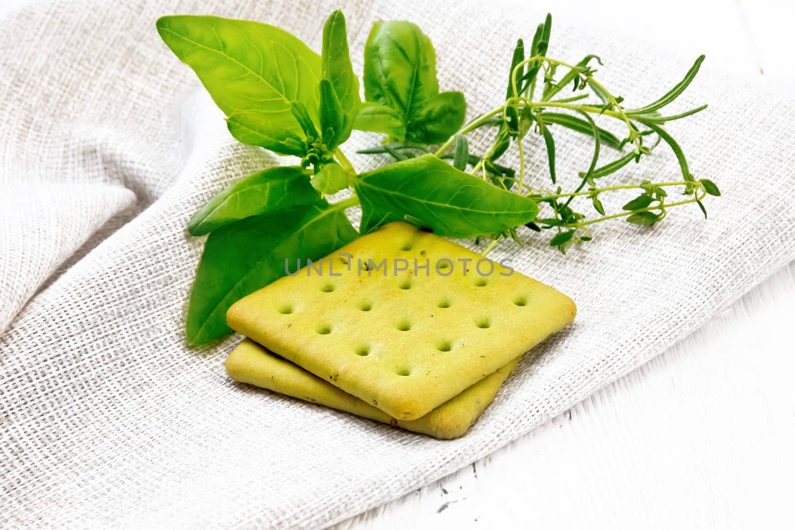 Dry cookies with spinach, rosemary and thyme on a towel against a wooden board background