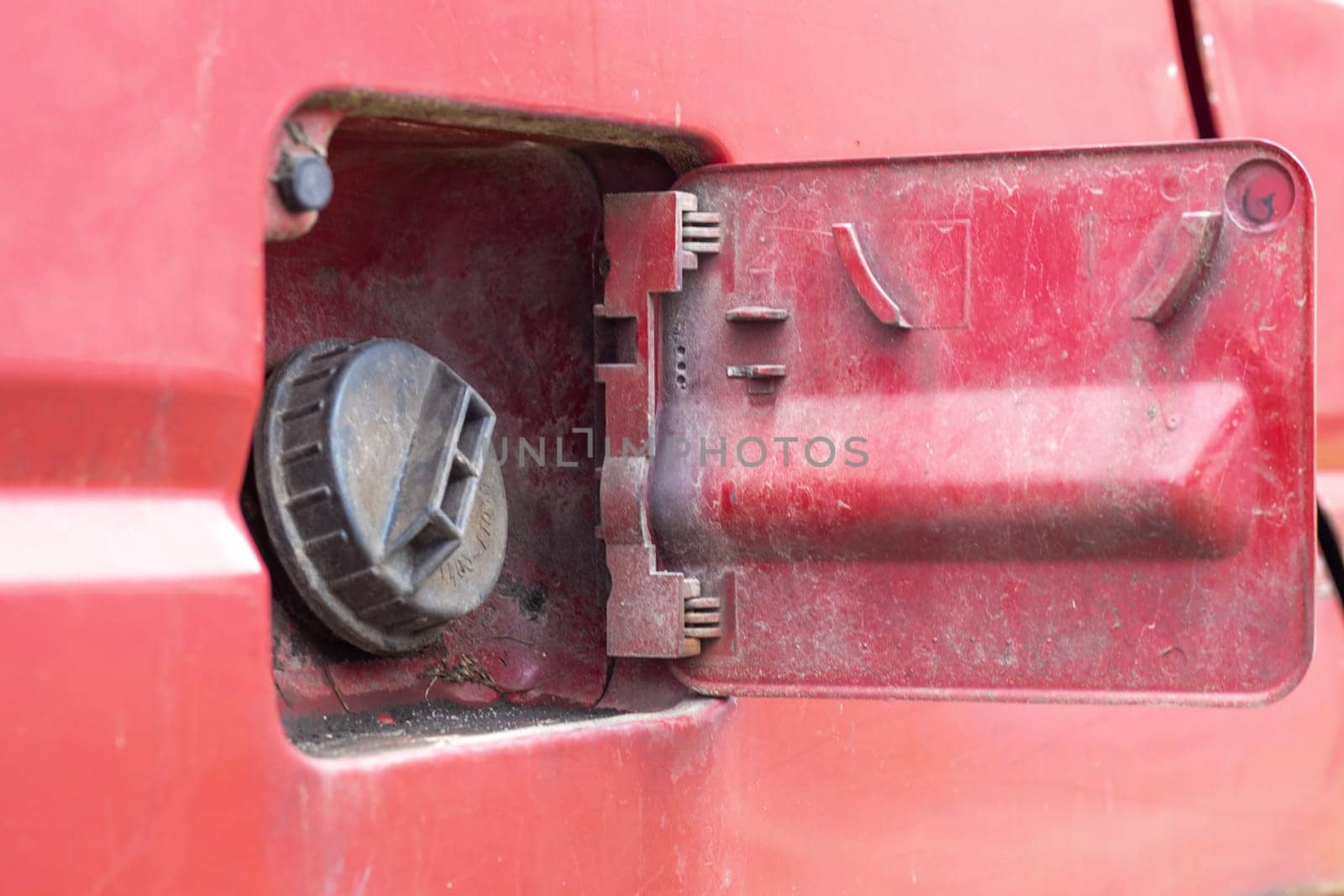 The car's open fuel tank cap was opened to pour gasoline or diesel fuel into the tank at a gas station. The concept of rising fuel prices and transport industry