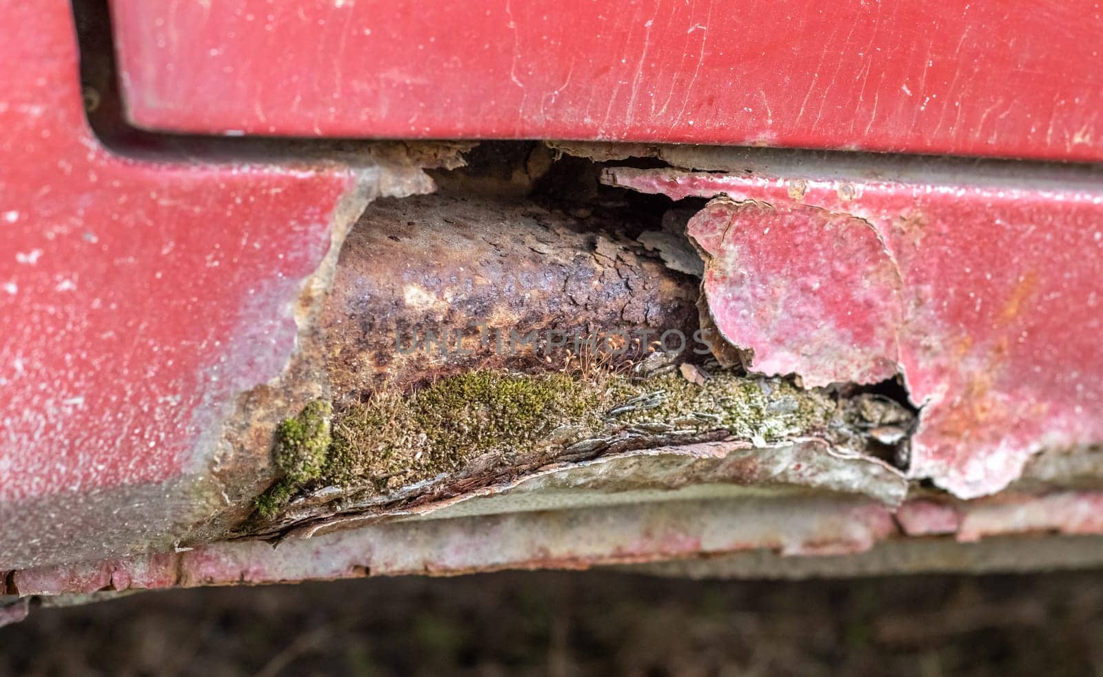 Rusty driver's door sills. Corrosion of the body of a red old car after winter. Influence of reagents in winter on an unprotected vehicle body. Damage to the left side, rotten threshold on the bottom