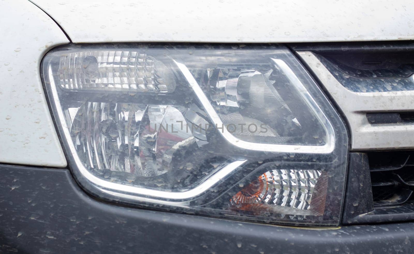 Front right headlight for Renault Duster. Crossover or SUV in white with a black bumper. View of the front of the car. Detailed close-up light on a car. Exterior detail. Ukraine, Kyiv - June 12. 2022