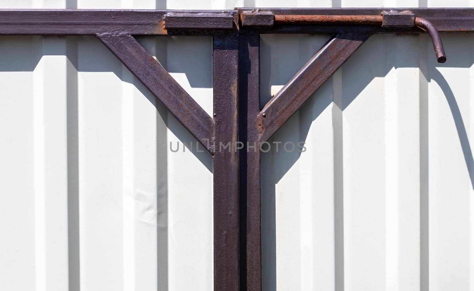 Latch on the gate. Design for locking the gate from the inside. Old rusty padlock on a metal fence. Locking latch on the gate