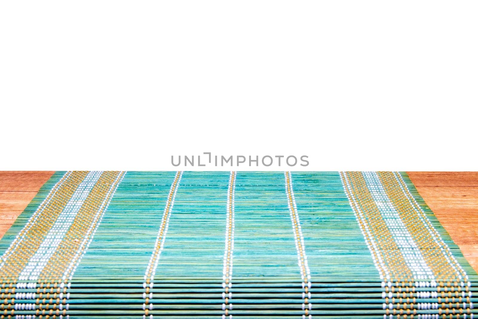 A green yellow bamboo mat on a rustic wooden table isolated on a white background. Template for your product display montage. Space for design.