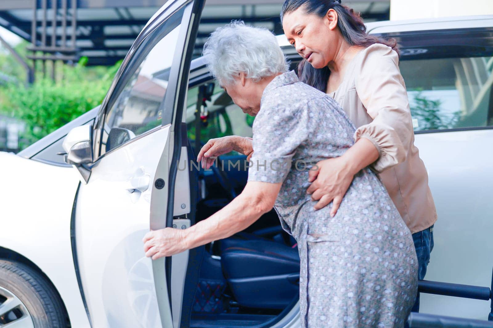 Caregiver help Asian elderly woman disability patient get in her car, medical concept.