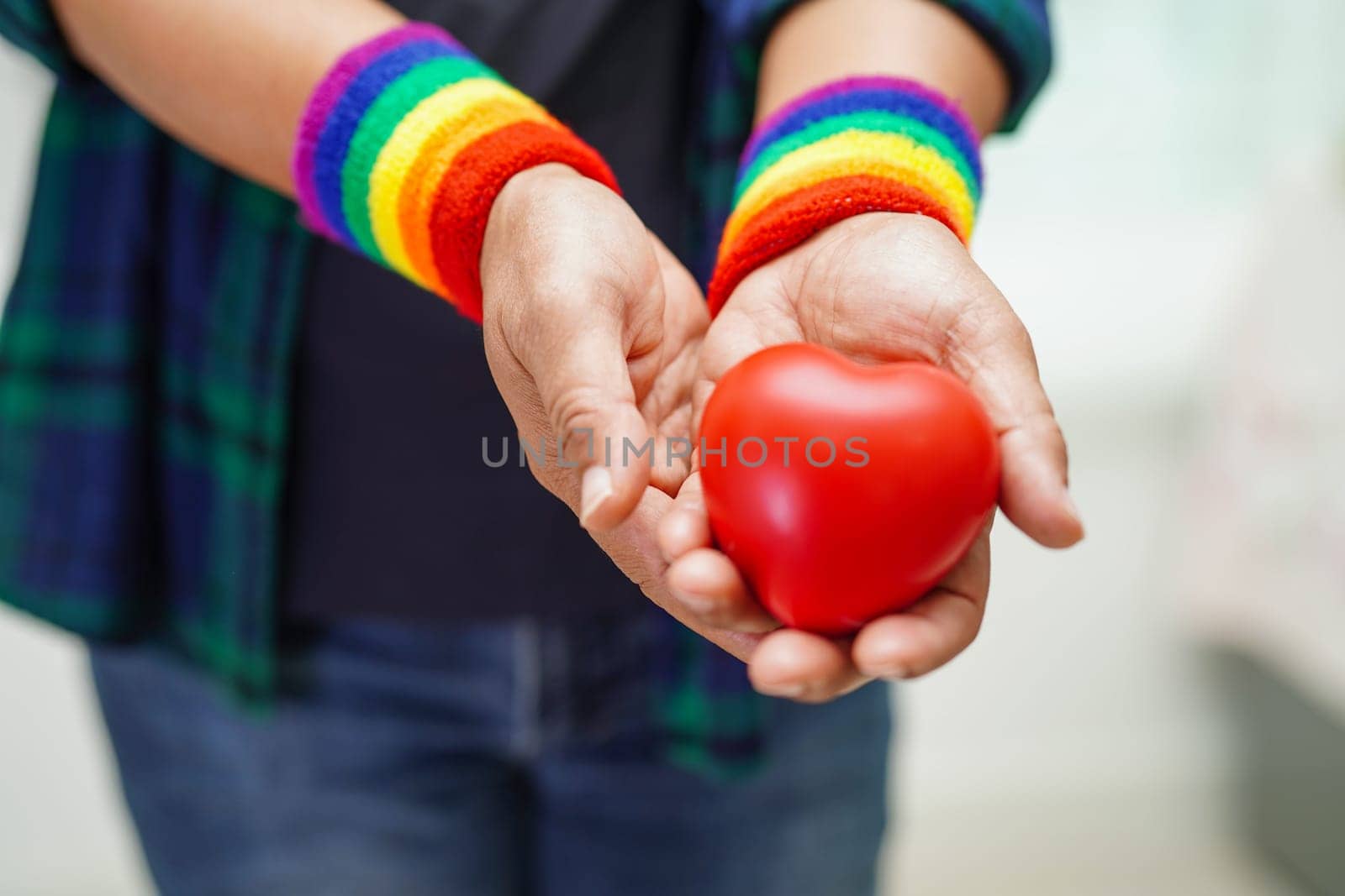 Asian woman holding red hert with rainbow flag, LGBT symbol rights and gender equality, LGBT Pride Month in June.
