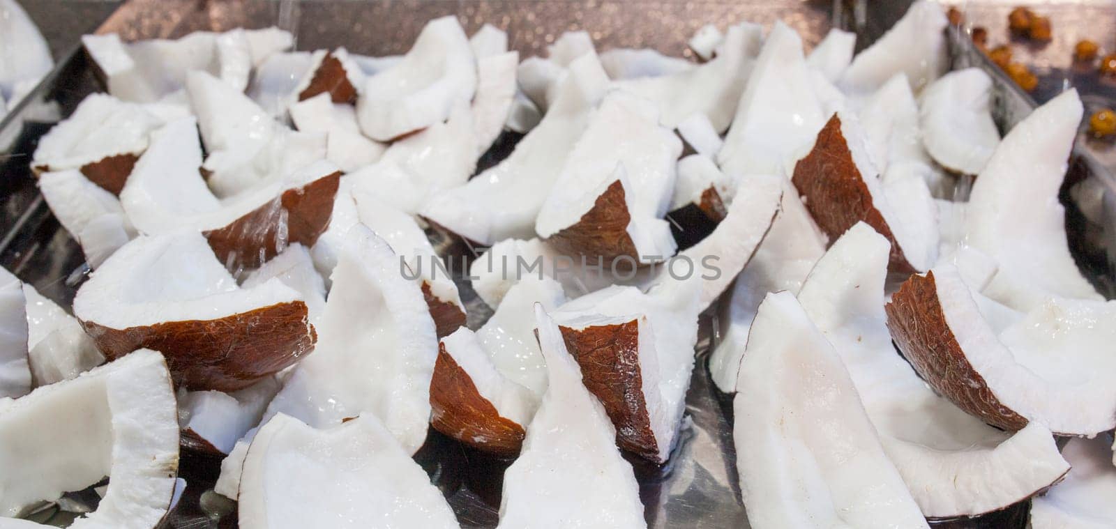 Fresh coconut slices. Water drops falling over pieces displayed at street market stall