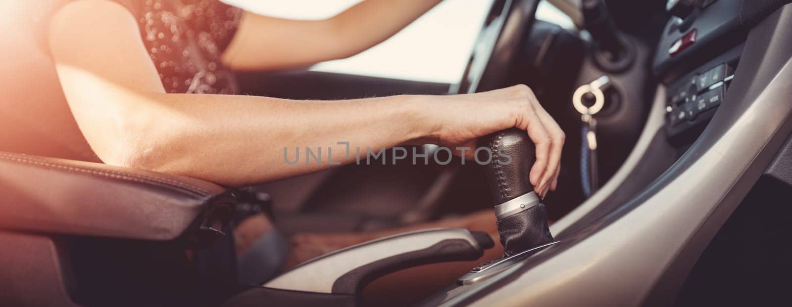 Woman driving a car and shifting gears on the gearbox. Concept of vacation and travel.