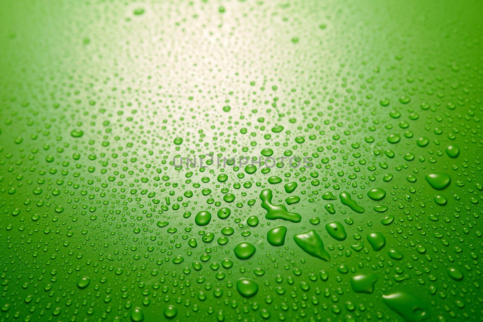 Full frame of clean green background covered with small round shaped drops of clear water flowing down in light room