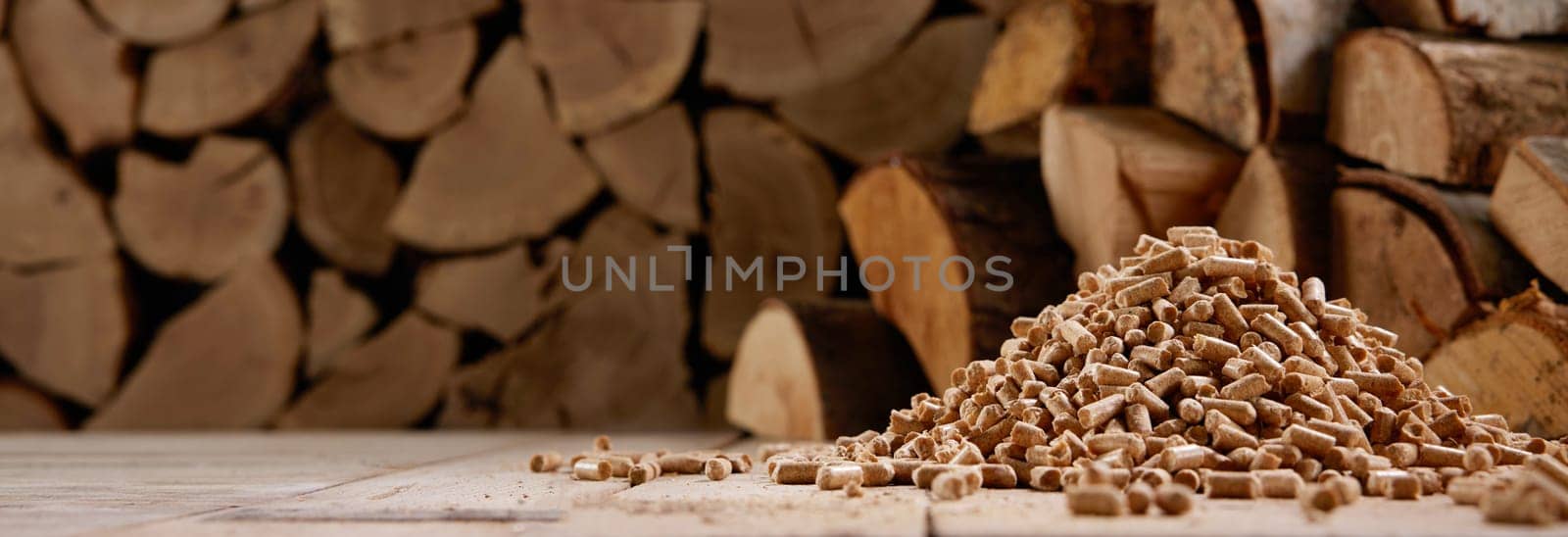 Ground level of pile of wood compressed fuel pellets stacked on floor near heap of firewood in sunlight