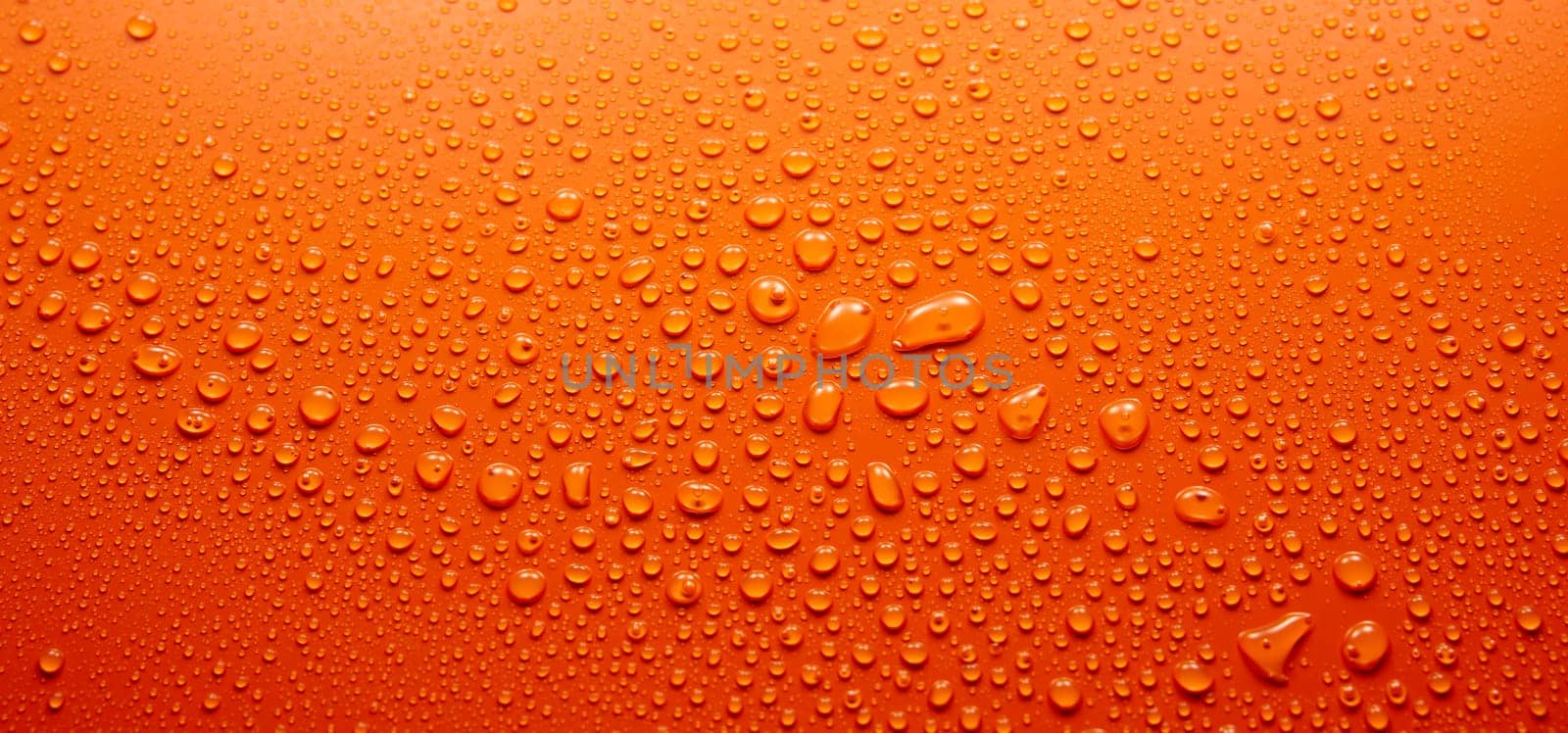 Panoramic view full frame of abstract clean orange background covered with various transparent round drops of water in light room