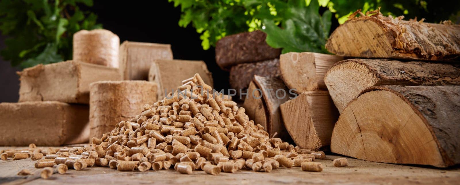 Stack of biomass briquettes with chopped firewood of various types placed on floor near heap of pellets in sunlight