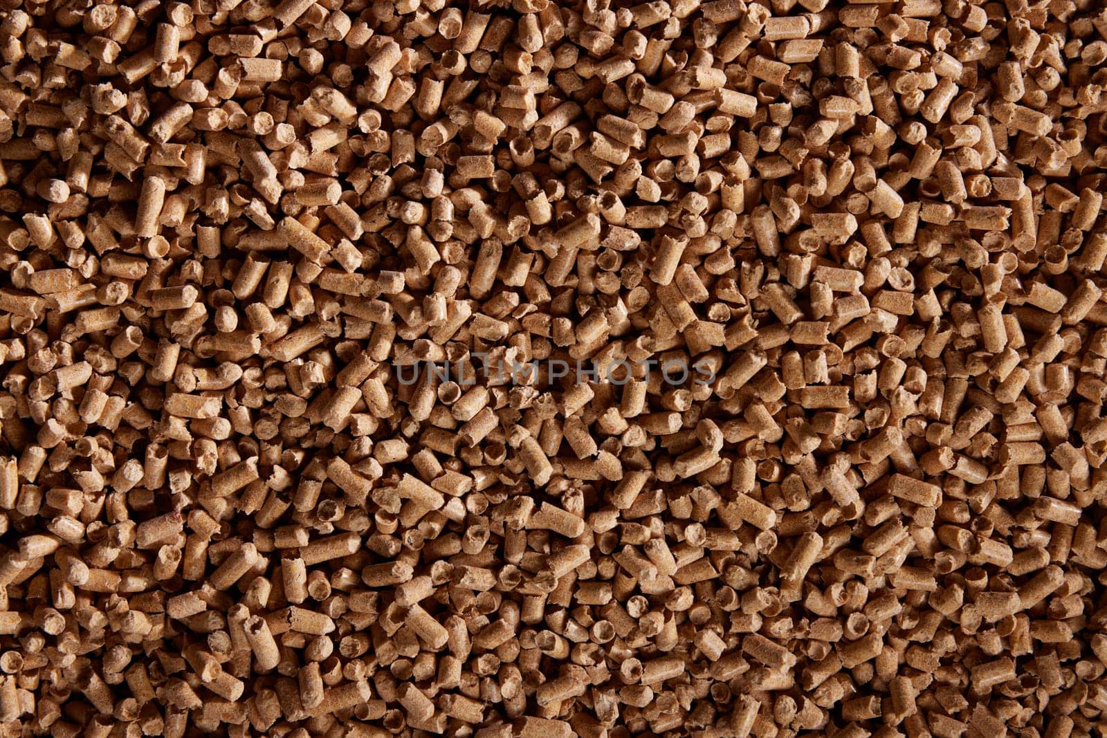 Top view of natural background of heap of cylindrical wood pellets scattered on surface in daytime