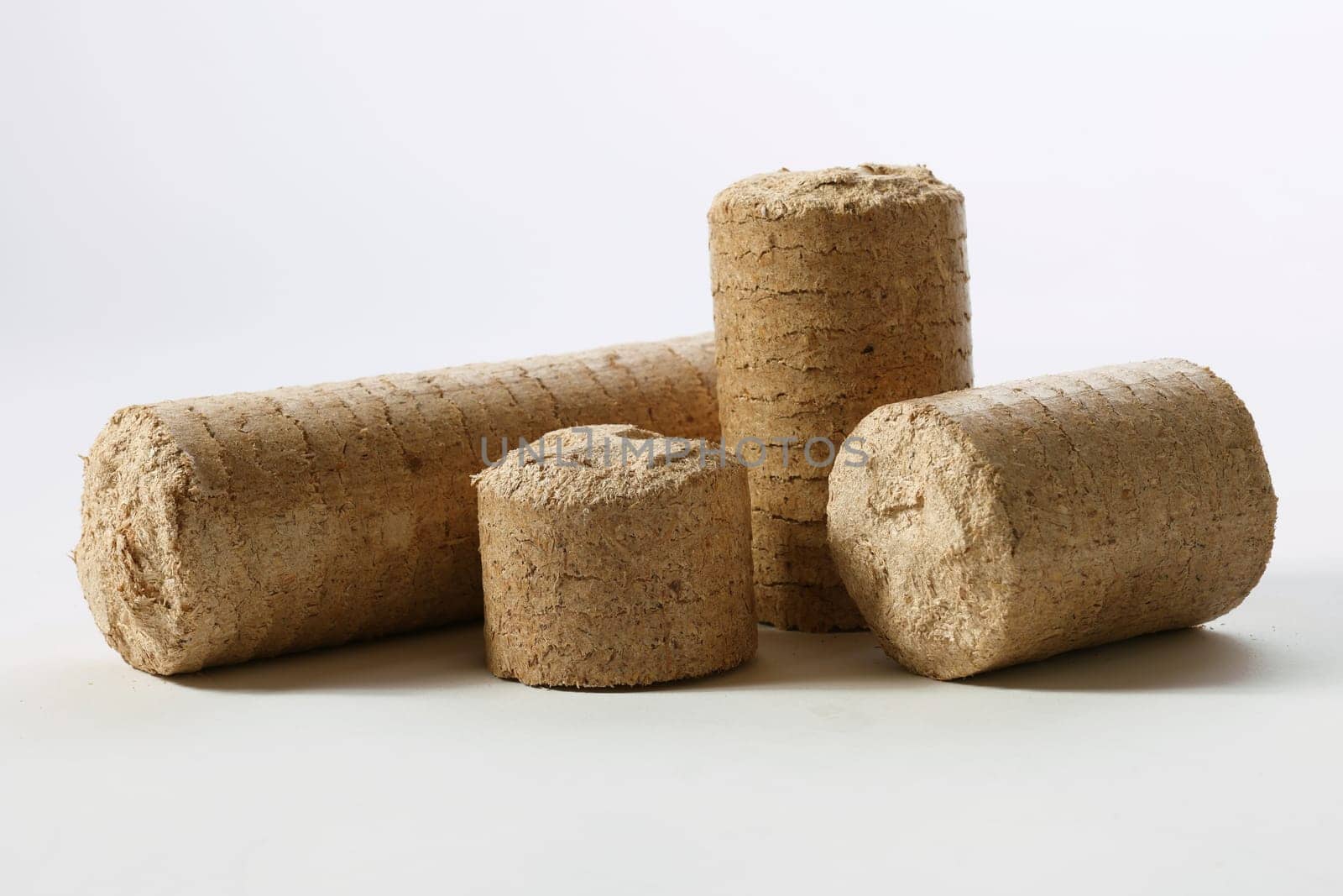 Cylinder shaped compressed solid biomass briquettes placed on white table in light studio
