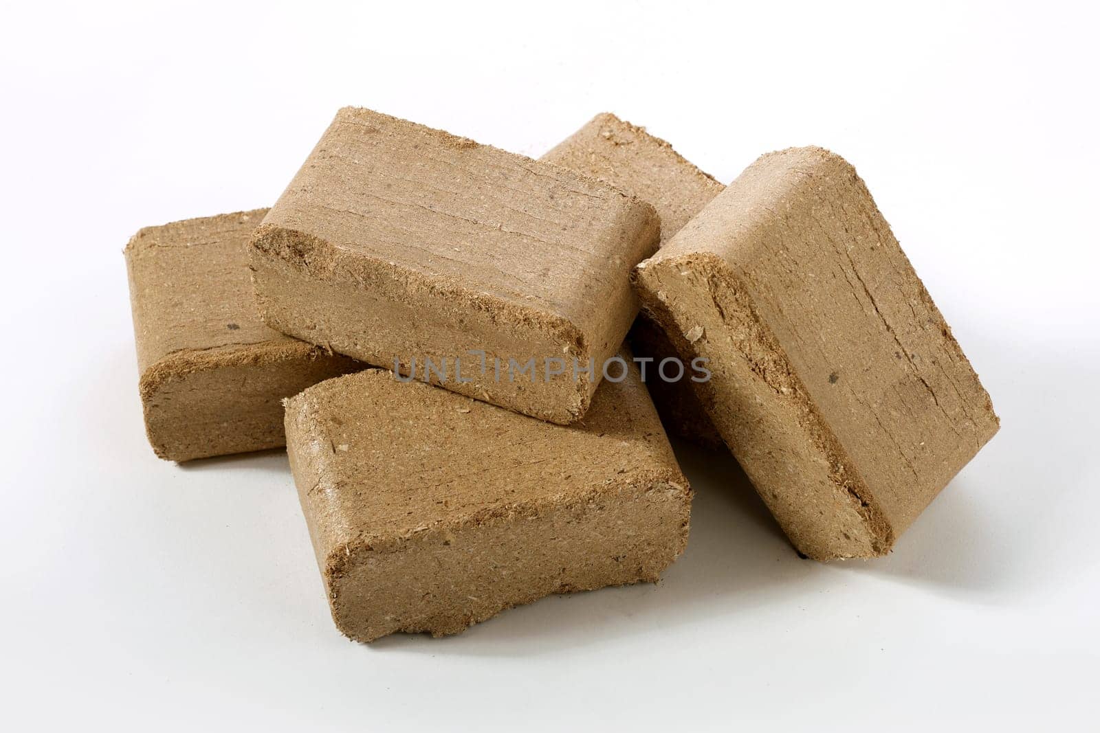 From above of brown briquettes of compressed biomass stacked on white surface in studio