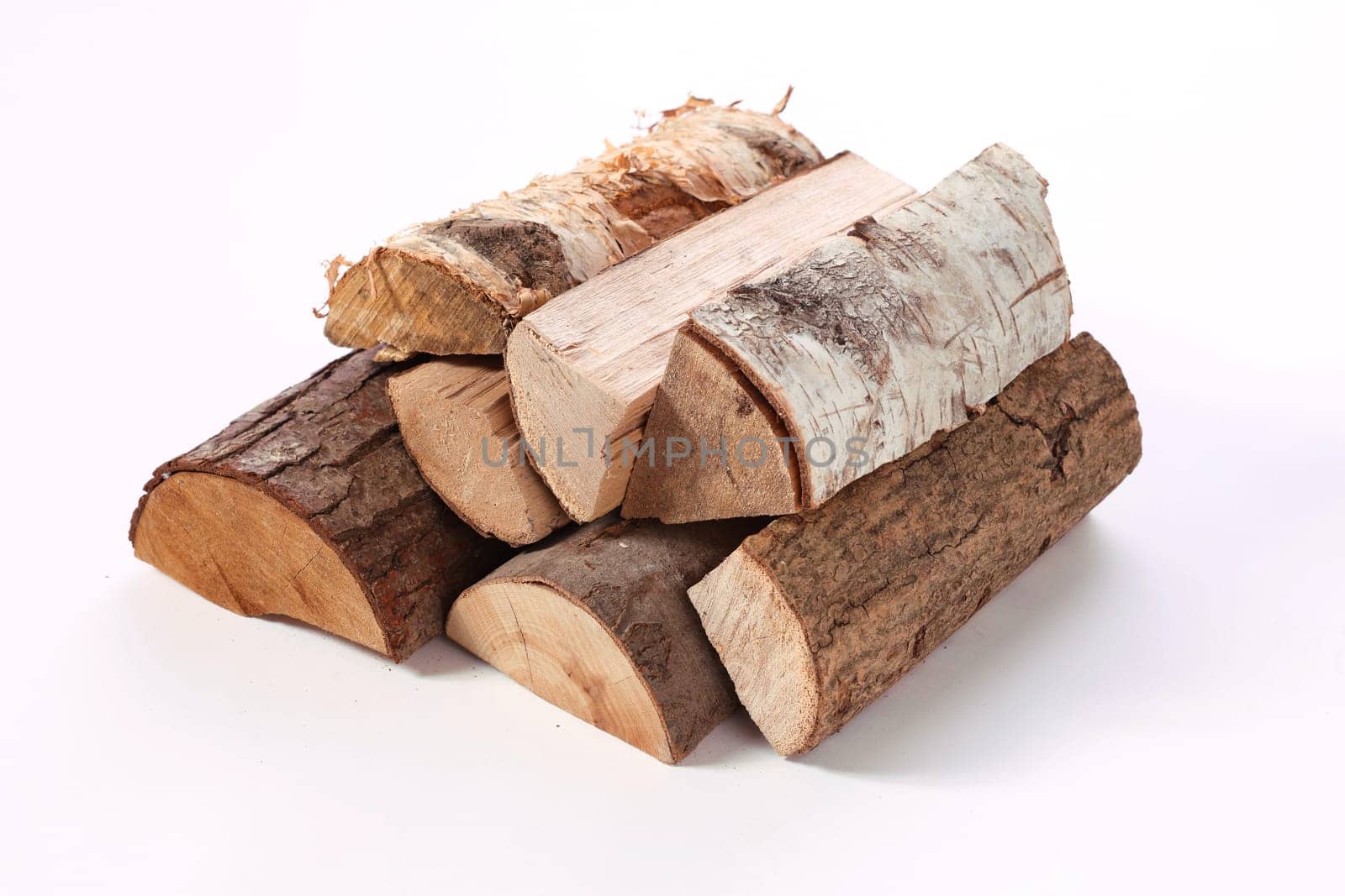 From above of solid chopped oak birch and pine firewood placed in stack on white surface