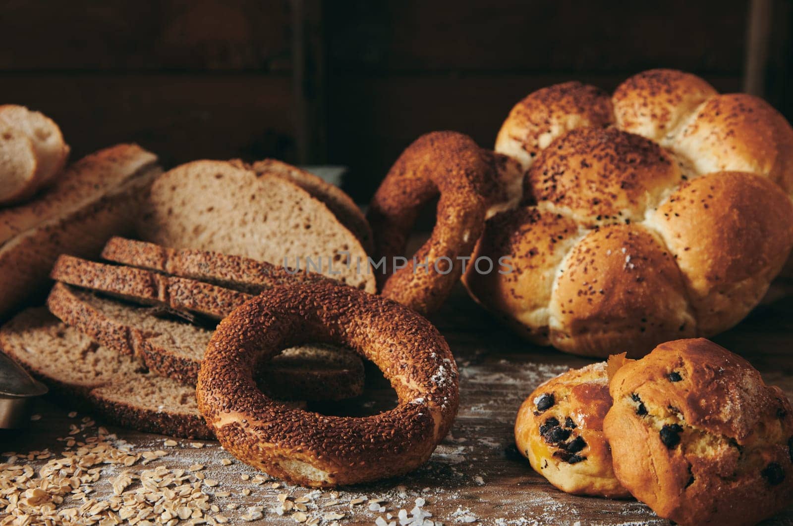Slices of fresh Turkish bread on table with mix of sweet baked pastry and buns in light kitchen of bakery