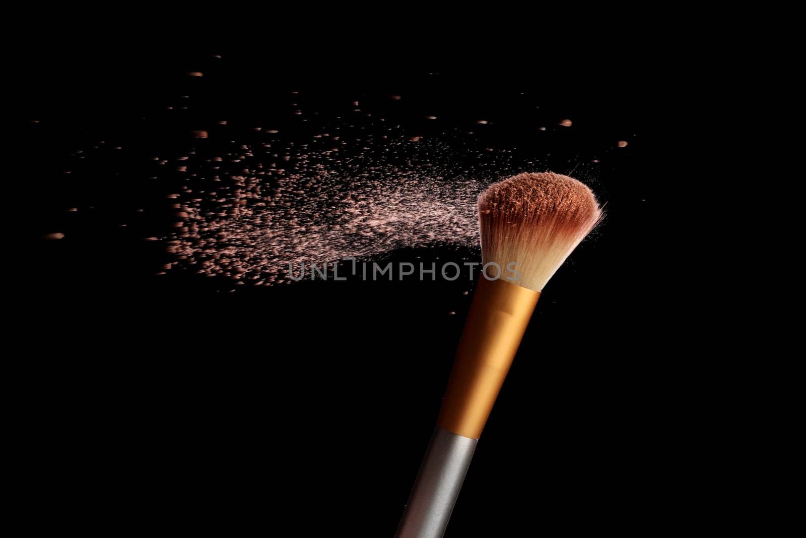 Make up brush with cosmetic powder splash, over black background. Splash image