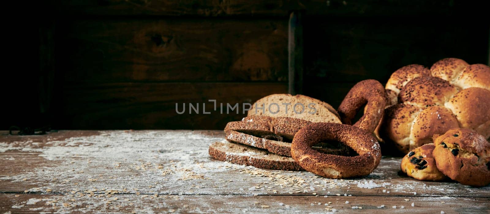 Slices of baked Turkish bread and sweet fresh pastry placed on messy table covered with white flour in light kitchen