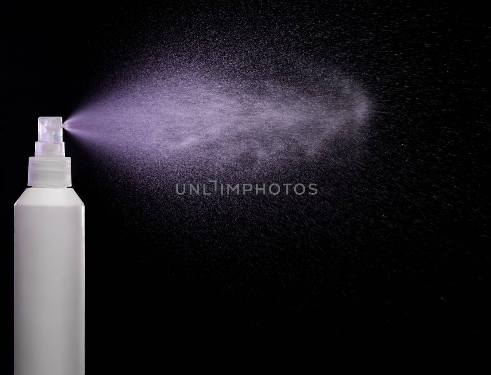 Spraying product in spray bottle over black background