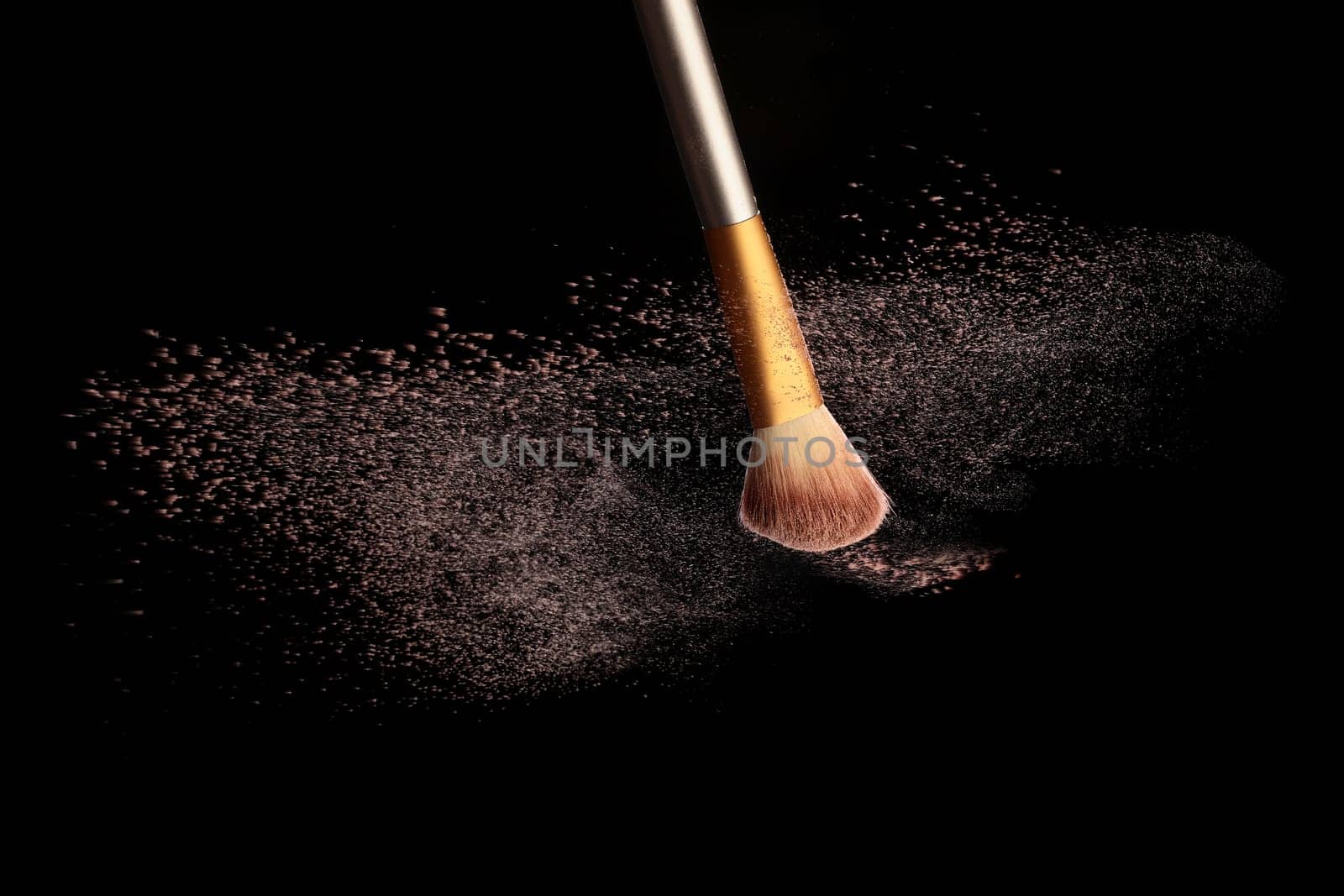 Make up brush with cosmetic powder splash, over black background. Splash image