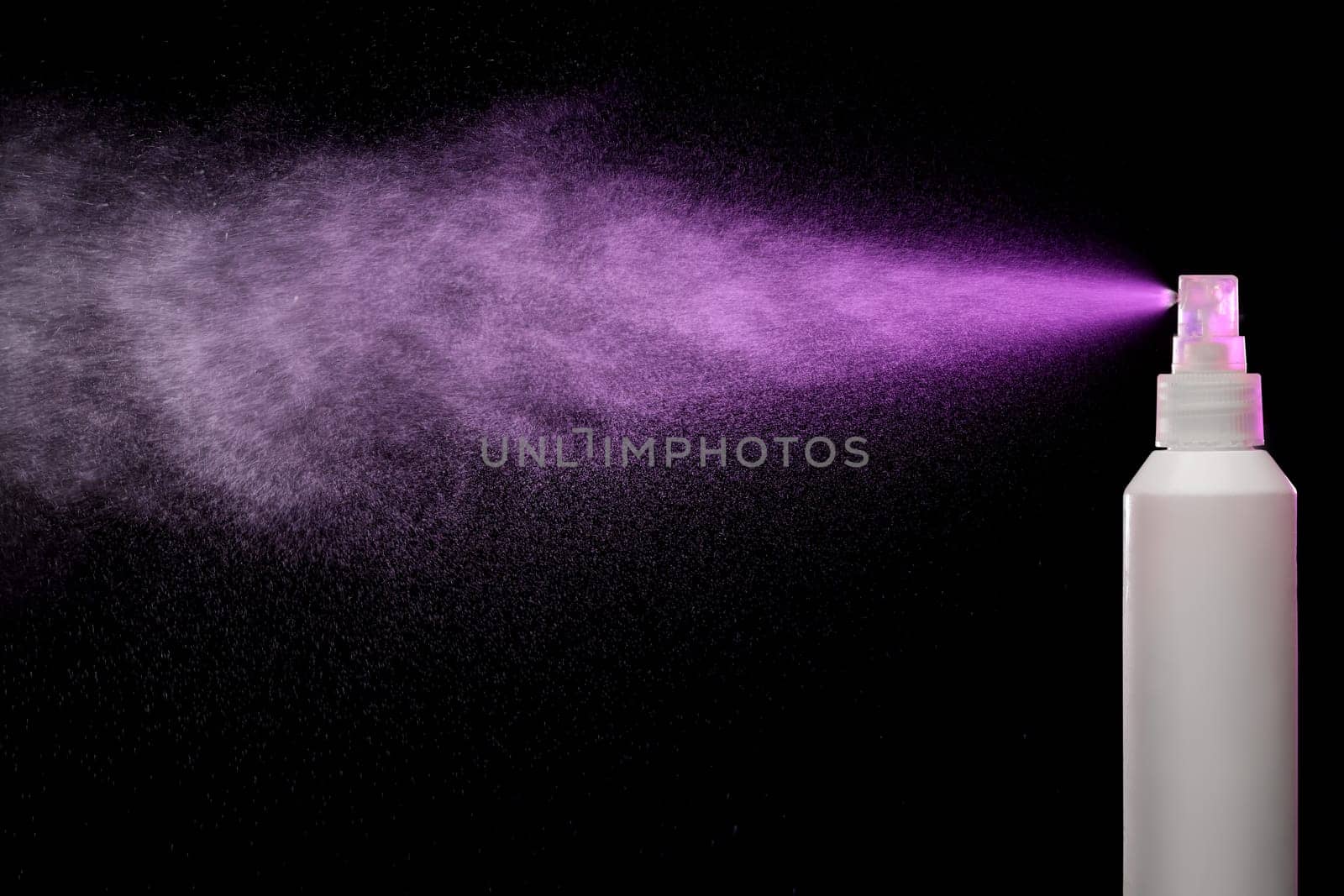 Spraying product in spray bottle over black background