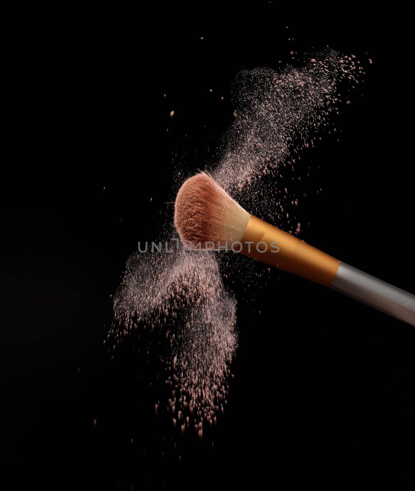 Make up brush with cosmetic powder splash, over black background. Splash image