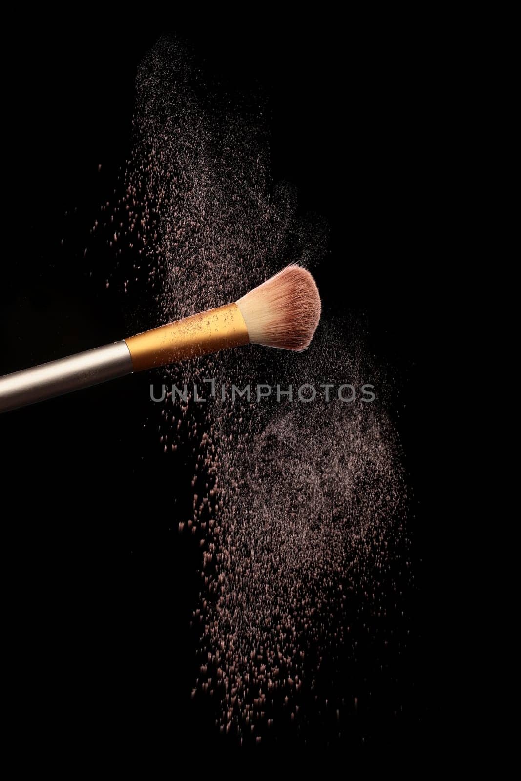 Make up brush with cosmetic powder splash, over black background. Splash image
