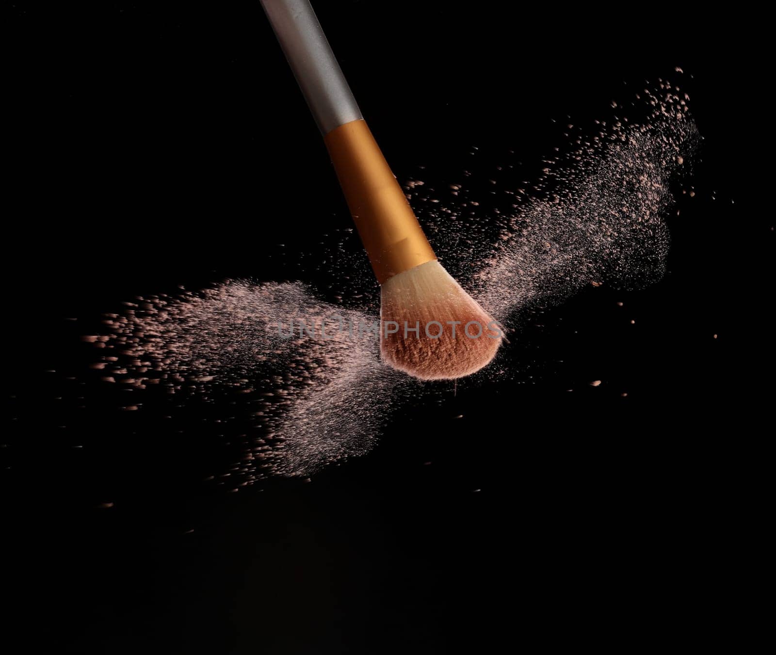 Make up brush with cosmetic powder splash, over black background. Splash image
