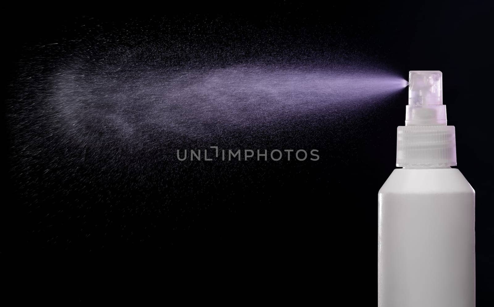 Spraying product in spray bottle over black background