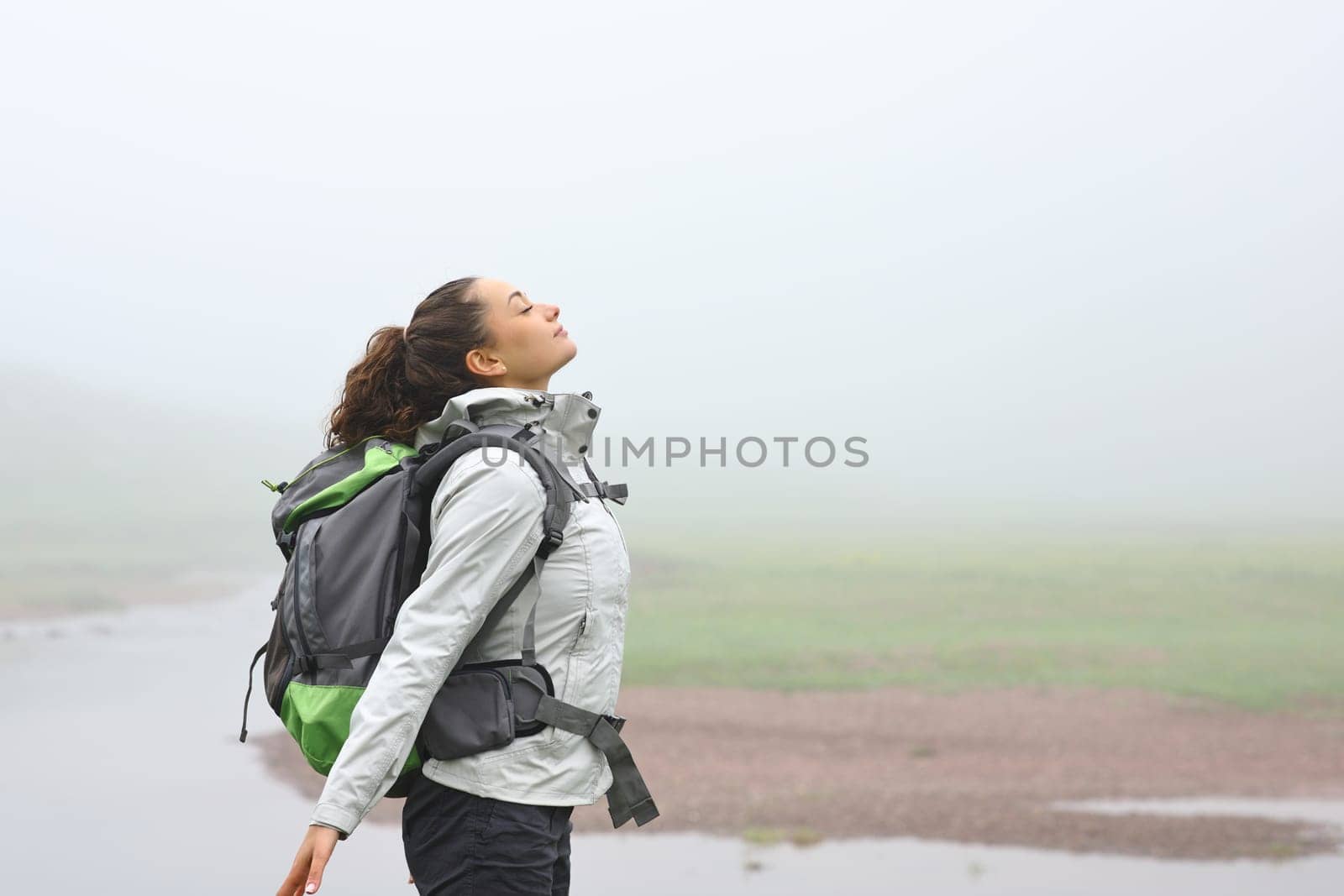 Side view portrait of a hiker breathing fresh air in the mountain a foggy day