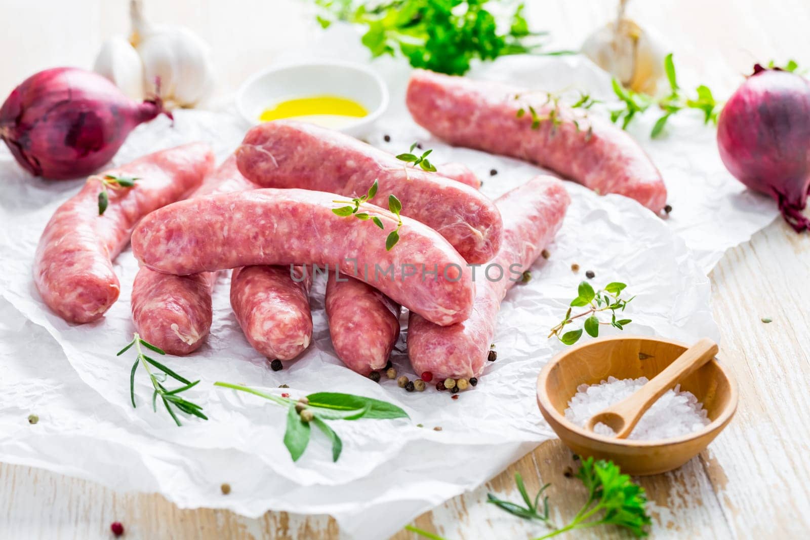 Raw sausages prepared for BBQ and grill with herbs and onions
