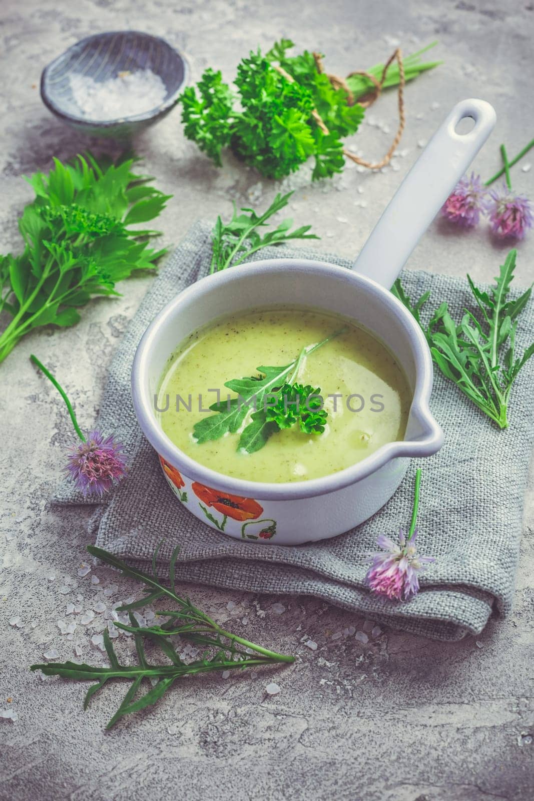 Healthy homemade green herb soup in pot made from local wild and garden herbs on grey