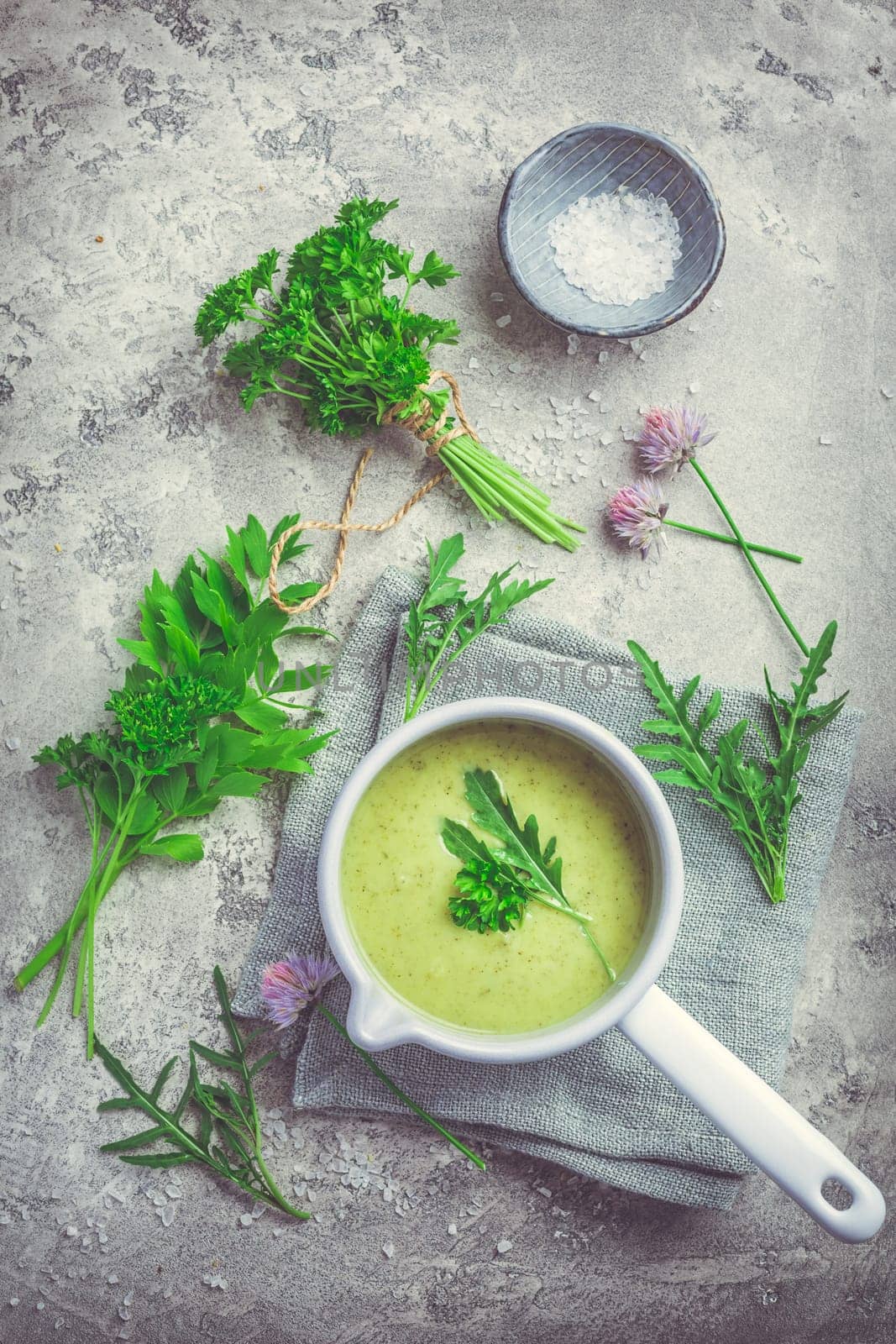Healthy homemade green herb soup in pot made from local wild and garden herbs on grey